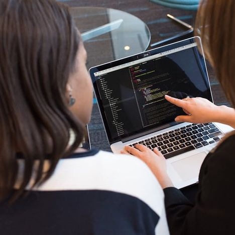 Two developers reviewing code together on a laptop